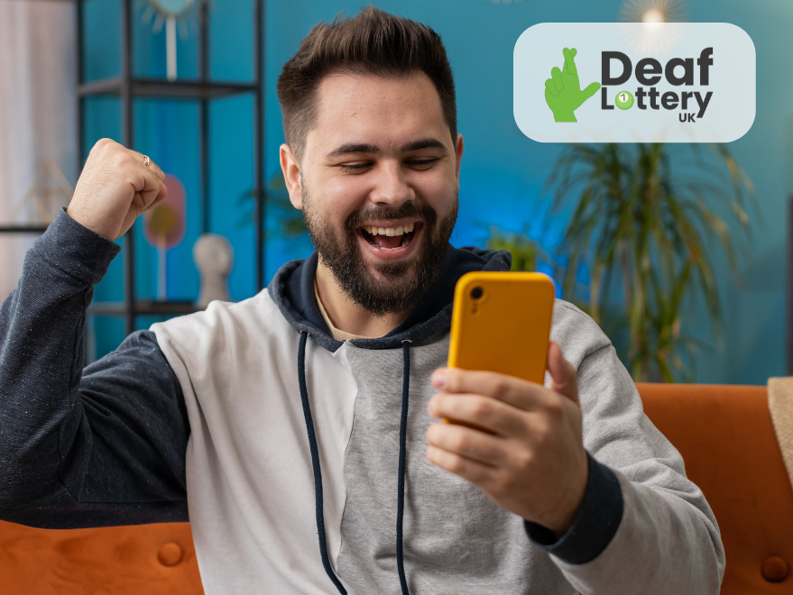 Person cheering at phone with the theme of winning the lottery. Deaf Lottery UK logo in background.