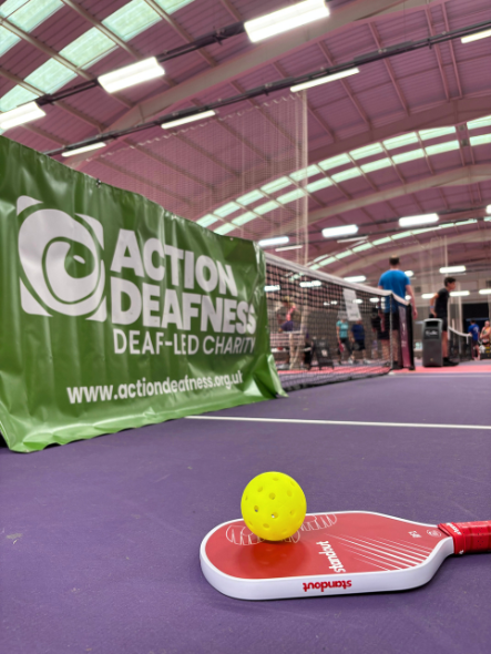 Pickleball paddle and ball alongside Action Deafness banner